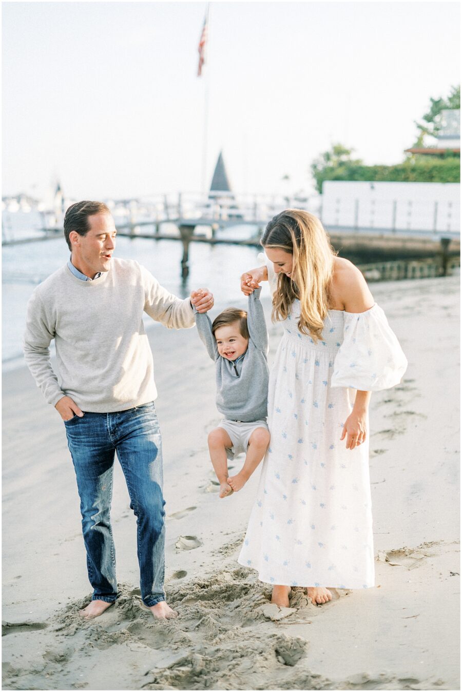 mom dad lifting up little boy on beach in Balboa