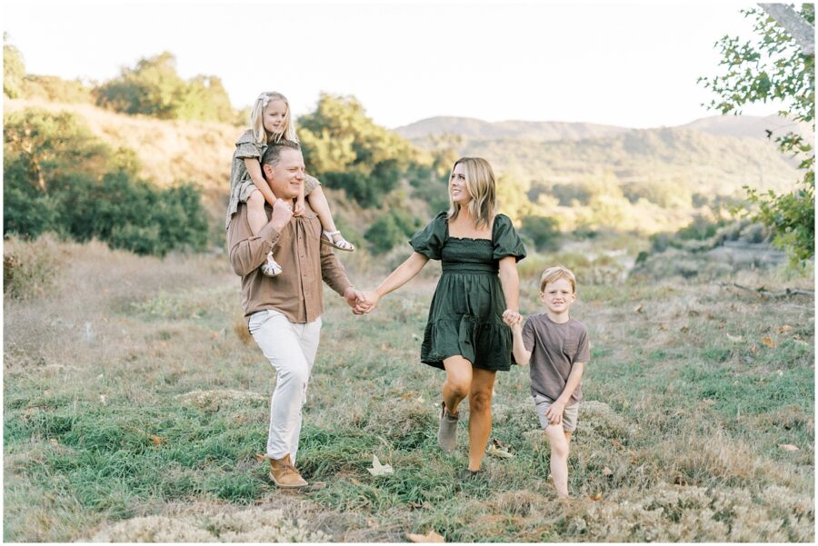 Family walking, holding hands in fall in Orange County grassy field