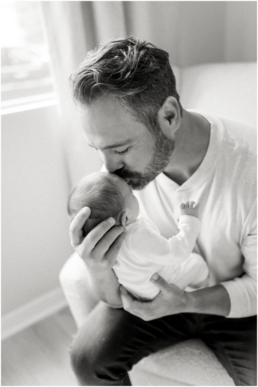 dad kissing newborn in black and white