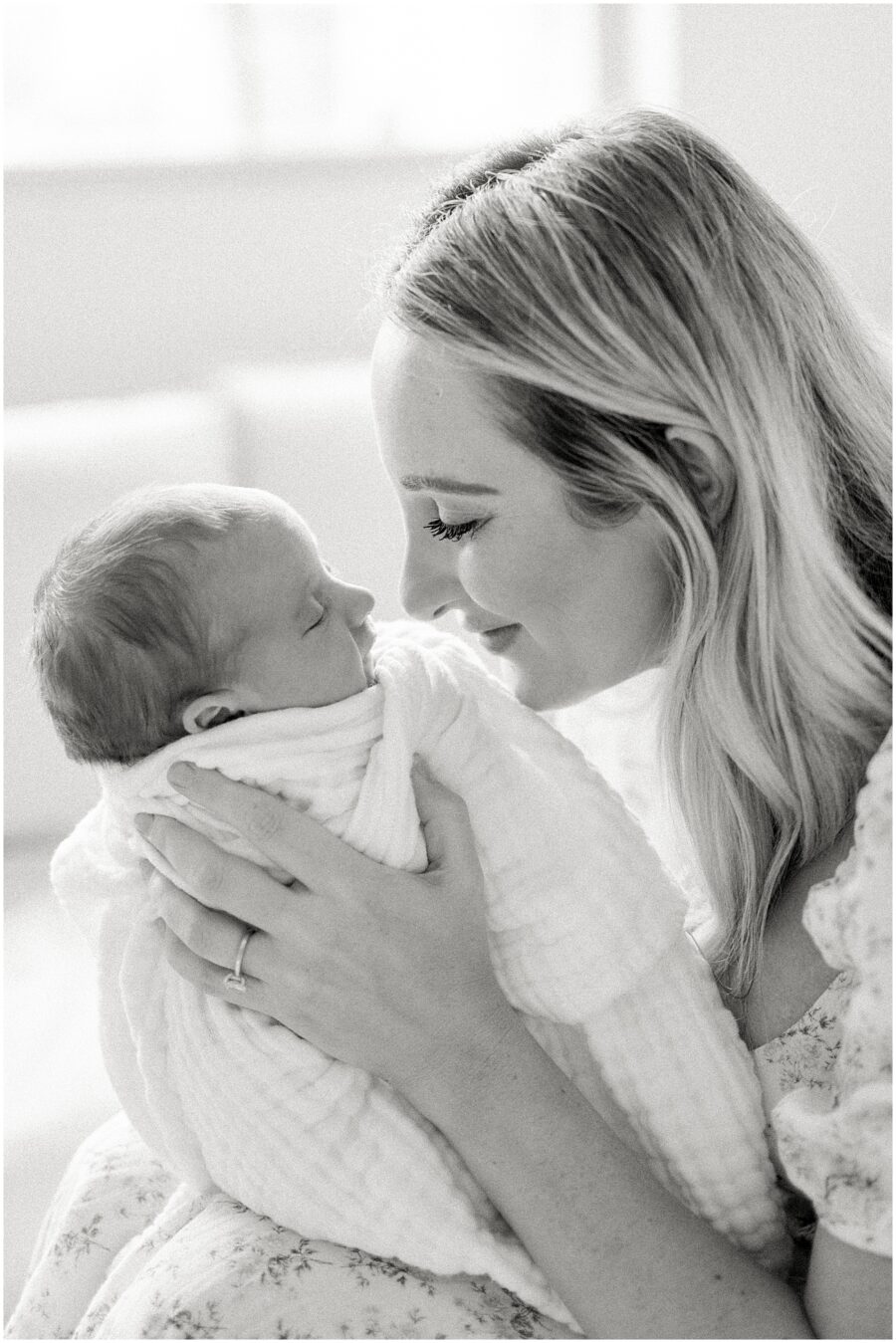 mom holding sleeping newborn close to face smiling in her Orange County home