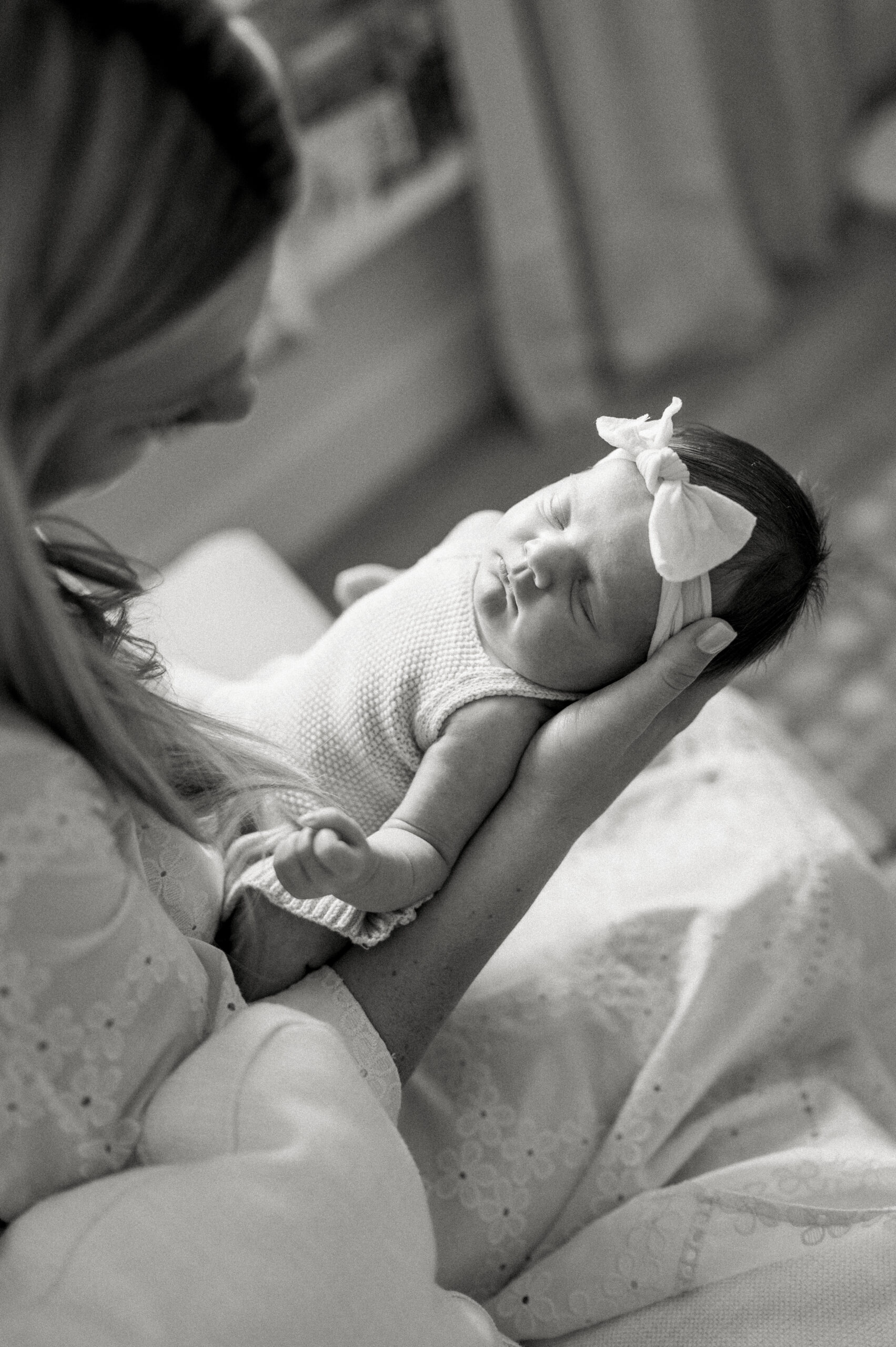 mom holding newborn baby in arms looking at her